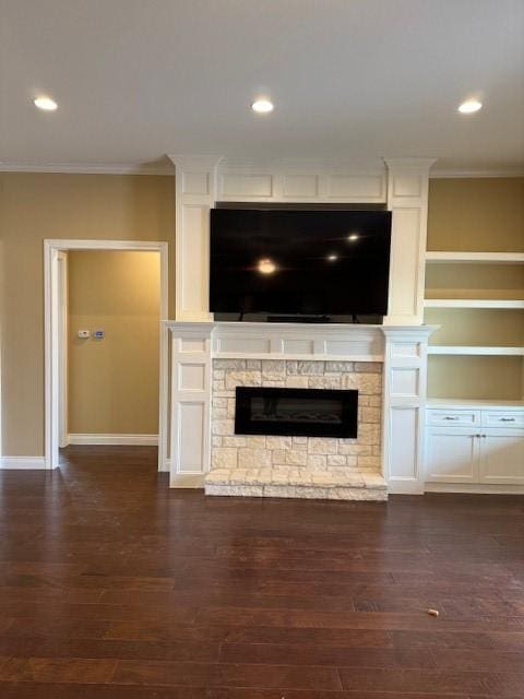 unfurnished living room featuring ornamental molding, a stone fireplace, and dark wood-type flooring