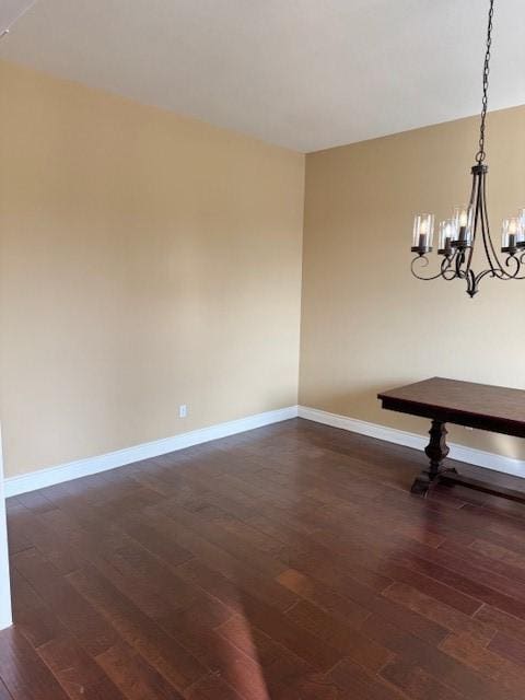 unfurnished dining area with a notable chandelier and dark wood-type flooring