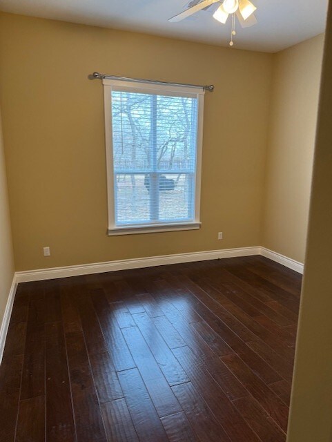 empty room with ceiling fan and dark hardwood / wood-style floors