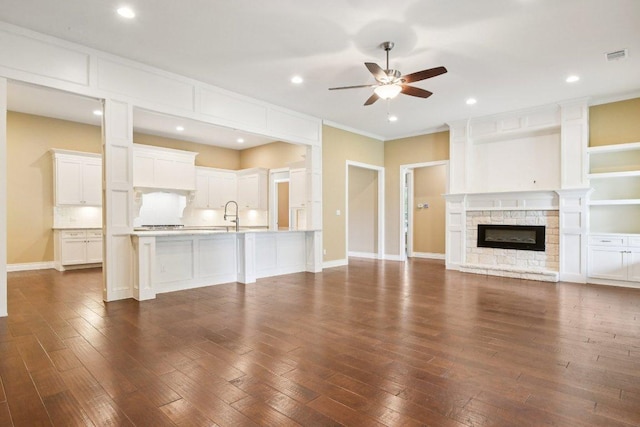 124 Abamillo Dr, Bastrop, TX 78602 - unfurnished living room with ceiling fan, dark wood finished floors, a fireplace, crown molding, and recessed lighting