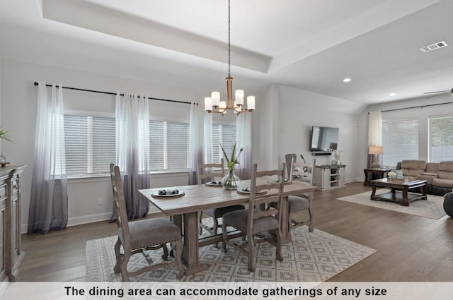 dining area featuring a raised ceiling, dark hardwood / wood-style floors, and a chandelier