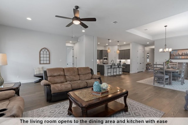 living room featuring wood-type flooring and ceiling fan with notable chandelier