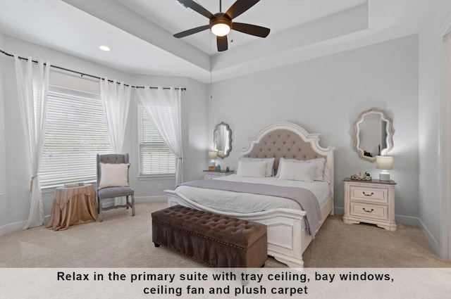 carpeted bedroom with ceiling fan and a tray ceiling