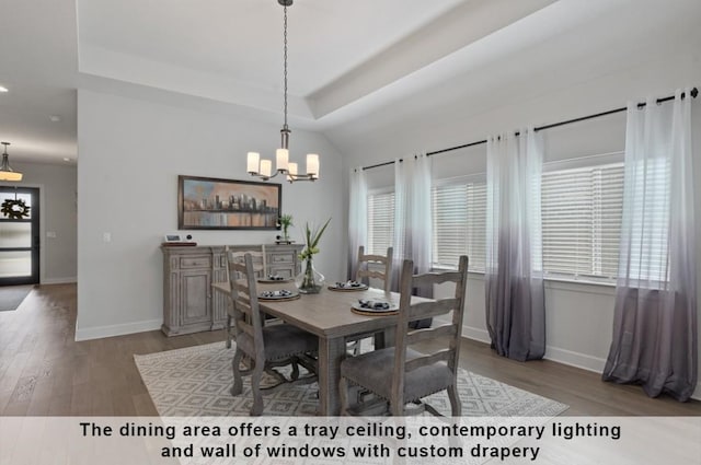 dining area with a tray ceiling, wood-type flooring, and a chandelier