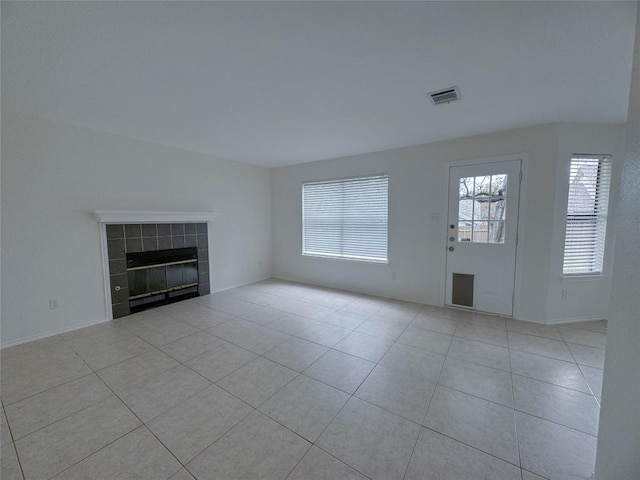 unfurnished living room featuring a tiled fireplace and light tile patterned flooring