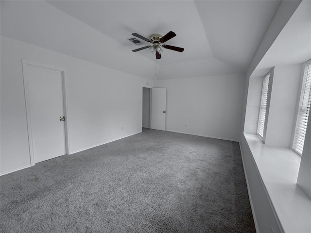 unfurnished room with ceiling fan, dark carpet, and a tray ceiling