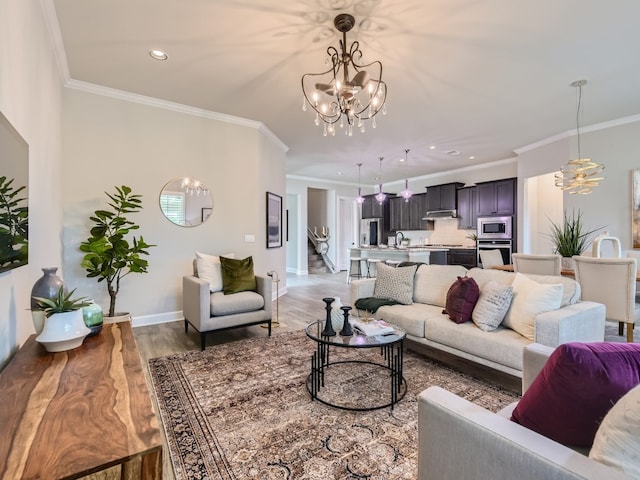 living room with an inviting chandelier, ornamental molding, and hardwood / wood-style floors