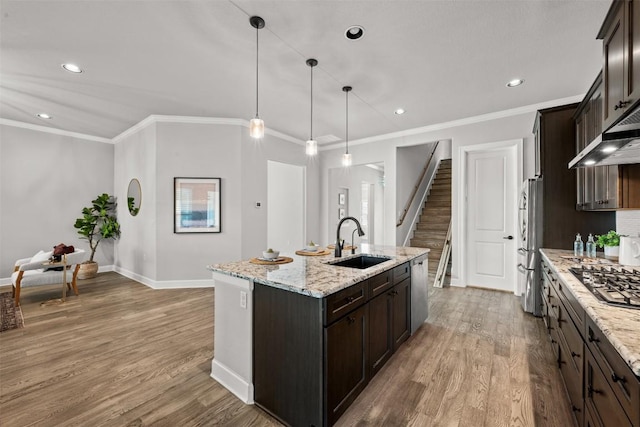 132 Drawing Maple St, San Marcos, TX 78666 - kitchen with stainless steel appliances, light wood finished floors, dark brown cabinets, a kitchen island with sink, and recessed lighting