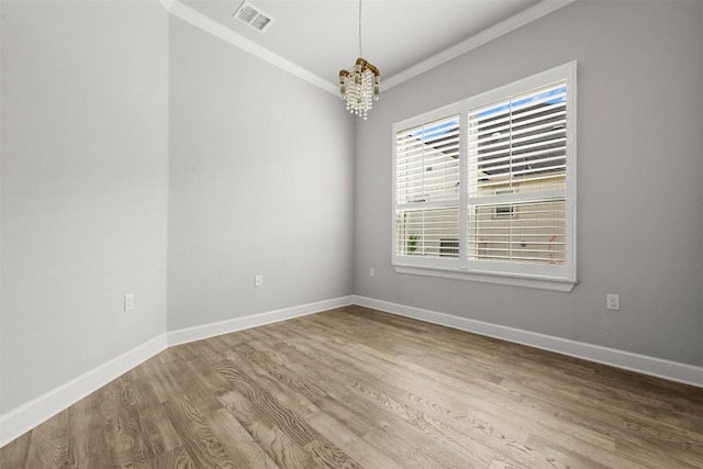 empty room with baseboards, ornamental molding, visible vents, and wood finished floors