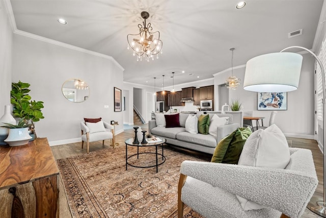 living area featuring wood finished floors, visible vents, baseboards, and a notable chandelier