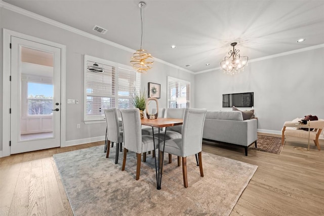 dining space with a chandelier, ornamental molding, visible vents, and wood finished floors