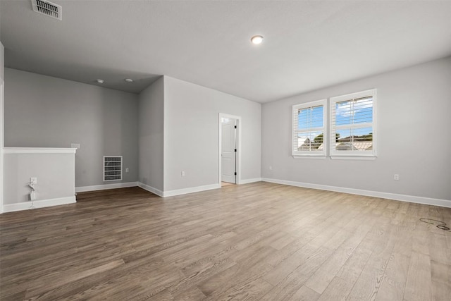 unfurnished room featuring baseboards, visible vents, and wood finished floors