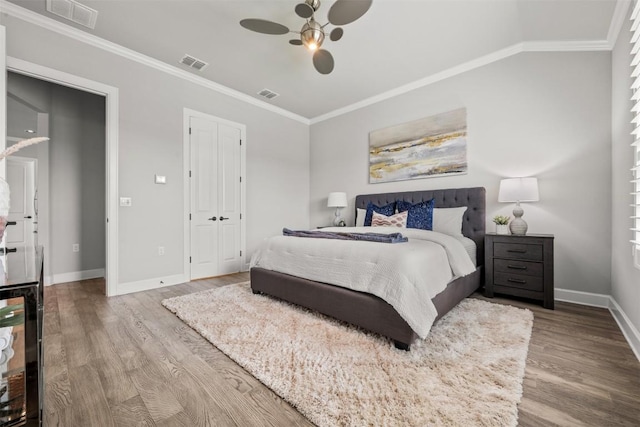 bedroom featuring crown molding, visible vents, wood finished floors, and baseboards
