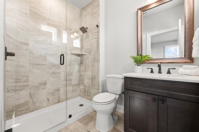full bath featuring a stall shower, baseboards, vanity, and toilet