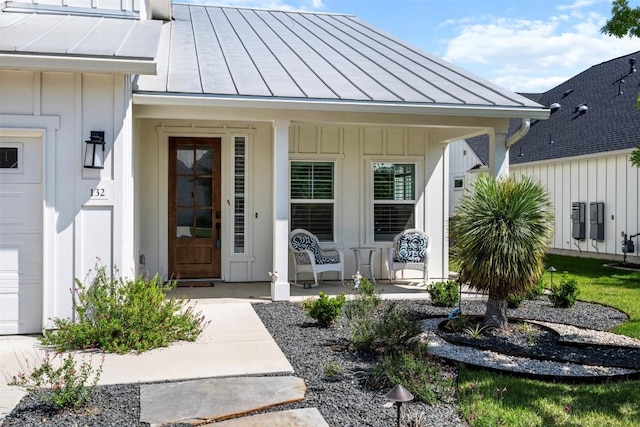 property entrance with board and batten siding, a standing seam roof, covered porch, and metal roof