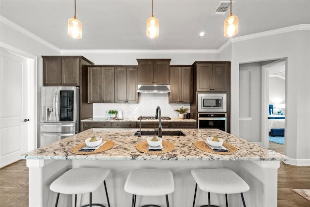 kitchen with dark brown cabinets, a sink, visible vents, under cabinet range hood, and appliances with stainless steel finishes