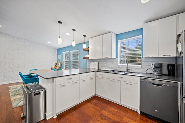 kitchen with sink, stainless steel dishwasher, kitchen peninsula, pendant lighting, and white cabinets