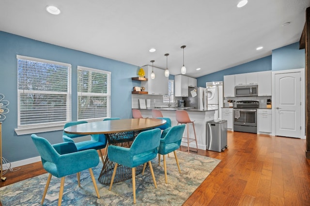 dining area with vaulted ceiling and light hardwood / wood-style flooring