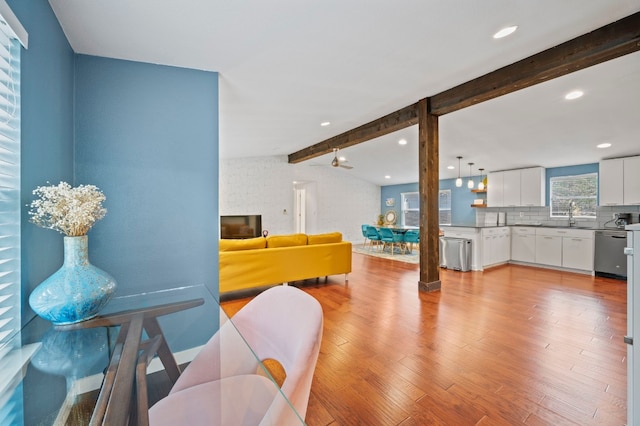 living room with vaulted ceiling with beams and light hardwood / wood-style flooring