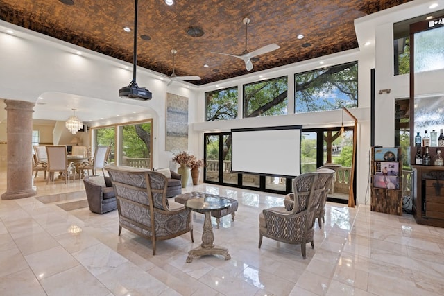 interior space featuring ceiling fan, a towering ceiling, and decorative columns