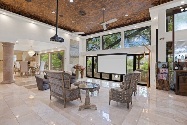 interior space with ceiling fan, a towering ceiling, and decorative columns