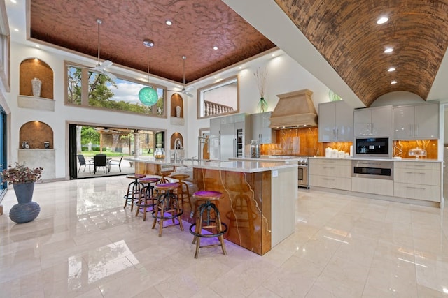 kitchen with white cabinetry, hanging light fixtures, a spacious island, high quality appliances, and custom range hood