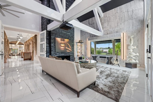 living room with ceiling fan, a fireplace, and a high ceiling