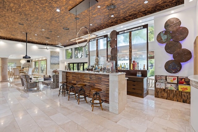 bar featuring a high ceiling, a wealth of natural light, and decorative columns