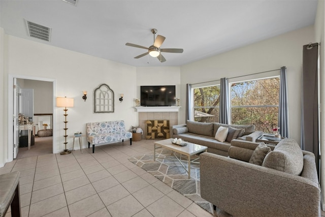 tiled living room with a fireplace and ceiling fan