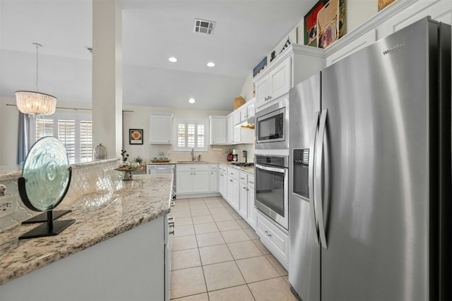 kitchen featuring stainless steel appliances, light tile patterned flooring, light stone countertops, and white cabinets