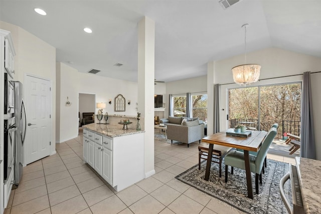 kitchen with light tile patterned floors, decorative light fixtures, light stone countertops, and white cabinets