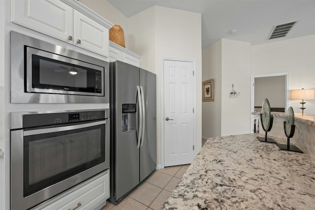 kitchen featuring stainless steel appliances, light stone countertops, light tile patterned floors, and white cabinets