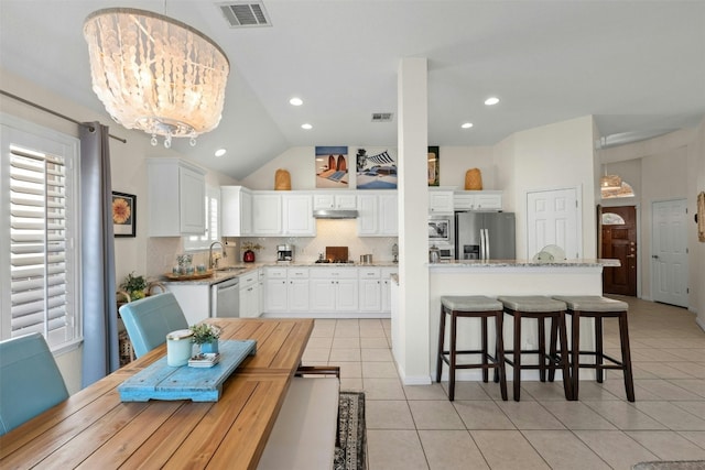 kitchen with white cabinetry, sink, hanging light fixtures, light tile patterned floors, and stainless steel appliances