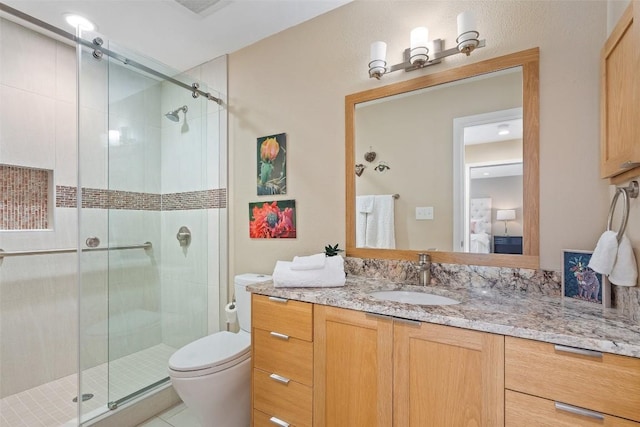 bathroom featuring vanity, toilet, and a shower with shower door