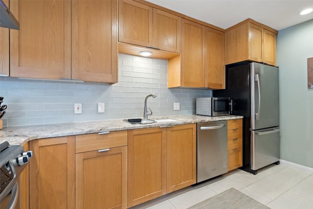 kitchen with sink, light tile patterned floors, backsplash, stainless steel appliances, and light stone countertops