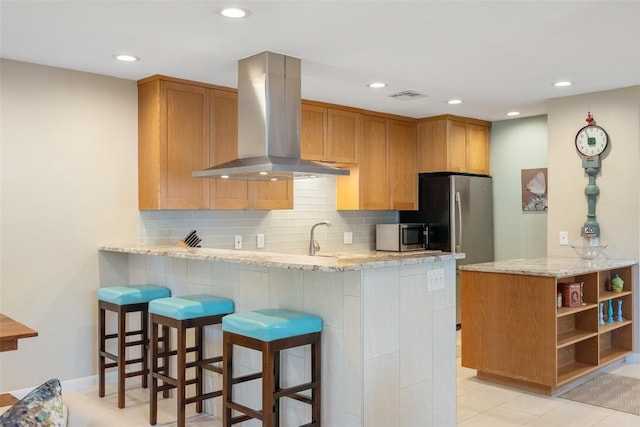 kitchen with backsplash, island range hood, kitchen peninsula, and appliances with stainless steel finishes