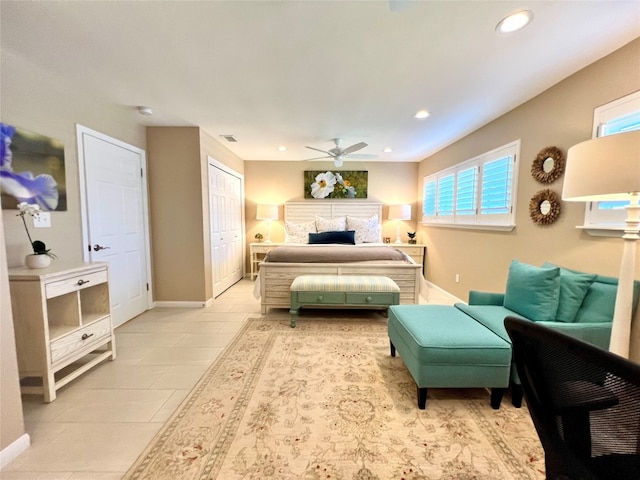 bedroom with light tile patterned flooring, ceiling fan, a fireplace, and multiple windows