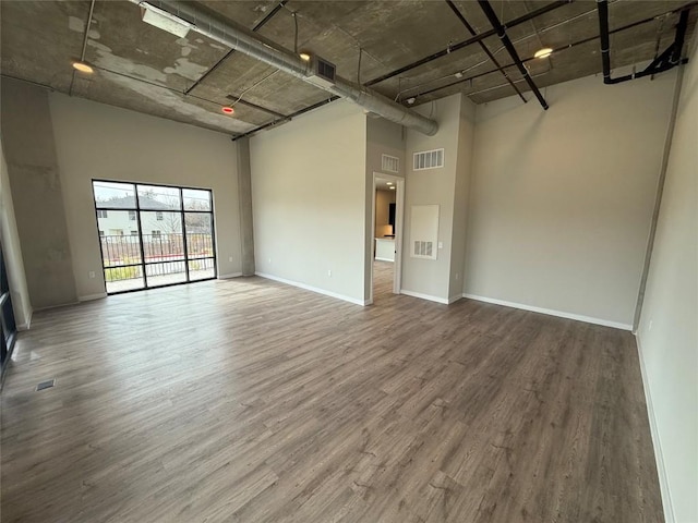 spare room with hardwood / wood-style floors and a towering ceiling