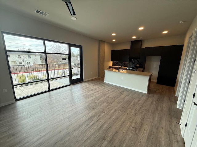 kitchen with a kitchen island with sink, hardwood / wood-style floors, decorative backsplash, and sink