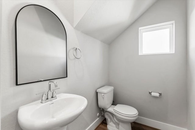 bathroom featuring vaulted ceiling, toilet, sink, and hardwood / wood-style floors