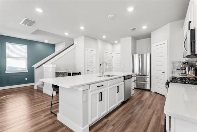 kitchen with white cabinetry, appliances with stainless steel finishes, sink, and an island with sink