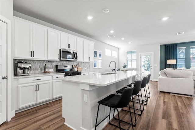 kitchen with stainless steel appliances, white cabinetry, a kitchen island with sink, and sink