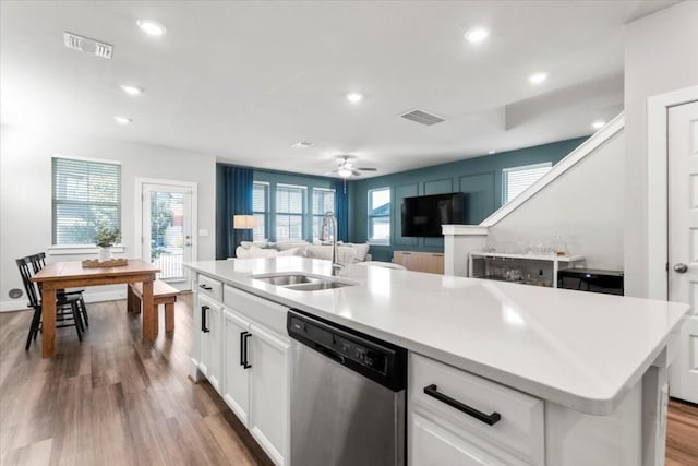 kitchen with white cabinets, dishwasher, sink, and an island with sink