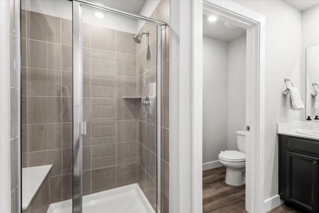 bathroom with vanity, wood-type flooring, a shower with shower door, and toilet