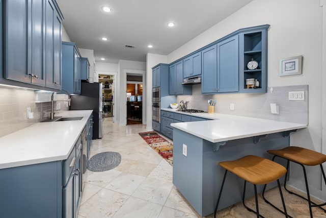 kitchen with blue cabinets, appliances with stainless steel finishes, sink, and kitchen peninsula