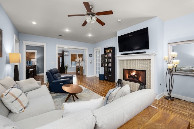 living room with ceiling fan, a fireplace, and light hardwood / wood-style flooring