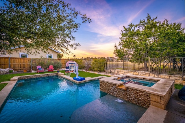 pool at dusk featuring pool water feature and an in ground hot tub