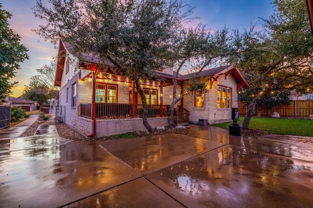 view of front of home featuring a front yard, stone siding, a patio area, and fence