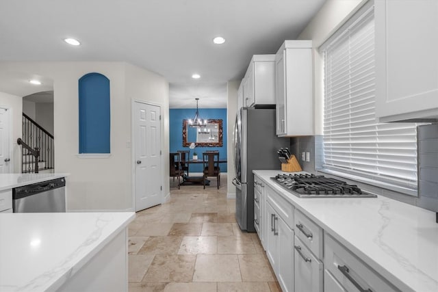 kitchen with an inviting chandelier, recessed lighting, stainless steel appliances, white cabinets, and backsplash