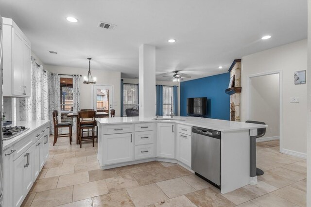 kitchen with white cabinetry, decorative light fixtures, kitchen peninsula, stainless steel appliances, and ceiling fan with notable chandelier